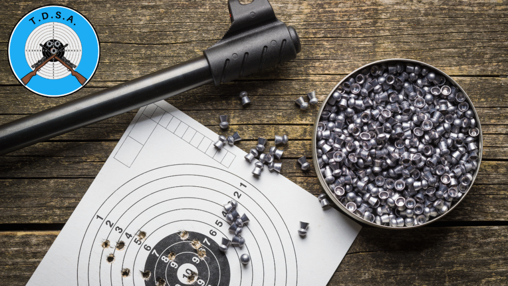 The Barrel of an air rifle on a table with a target and some pellets